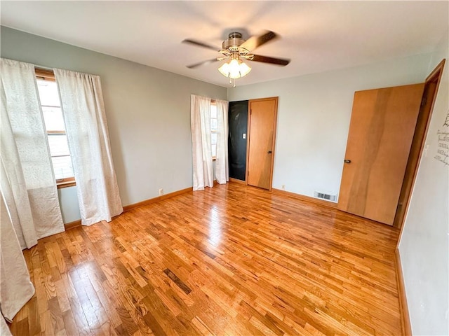 unfurnished bedroom featuring baseboards, a ceiling fan, visible vents, and light wood-style floors