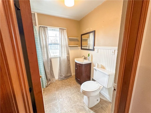 bathroom featuring a wainscoted wall, vanity, toilet, and tile patterned floors