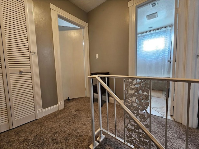 hallway with carpet flooring and an upstairs landing