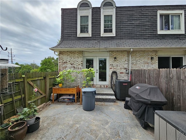 back of house featuring cooling unit, a patio area, a fenced backyard, and mansard roof