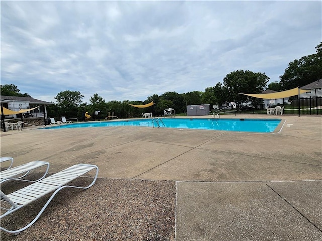 pool with a patio area and fence