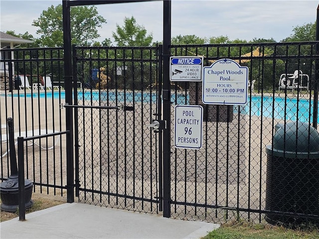 view of gate with fence and a community pool