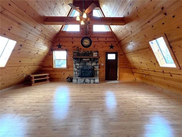 bonus room with lofted ceiling with skylight, wood walls, and wood finished floors