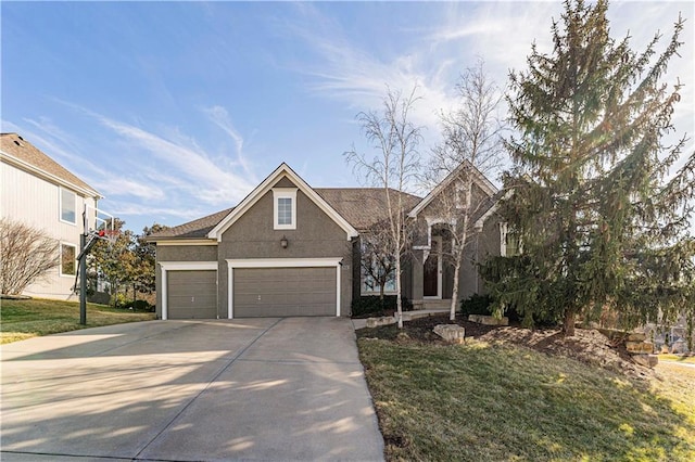 traditional-style home featuring an attached garage, driveway, and stucco siding