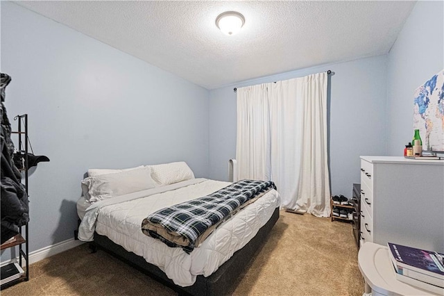 bedroom with baseboards, a textured ceiling, and light colored carpet