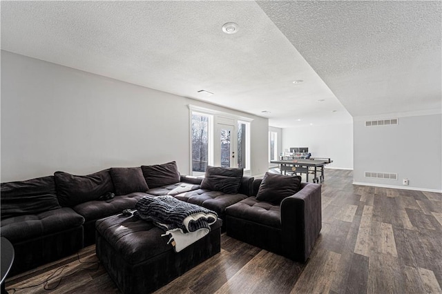 living room featuring dark wood-style floors, visible vents, and a textured ceiling