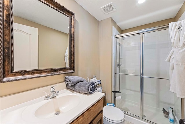 full bath with a stall shower, visible vents, vanity, and toilet