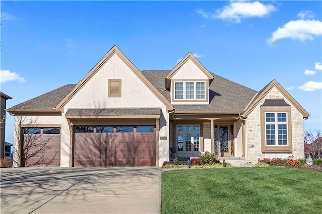 craftsman-style house with a front lawn, stone siding, a shingled roof, an attached garage, and driveway