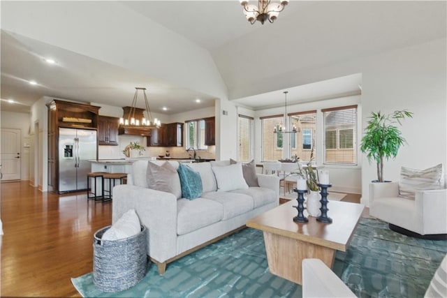 living room featuring a chandelier, recessed lighting, baseboards, dark wood-type flooring, and vaulted ceiling