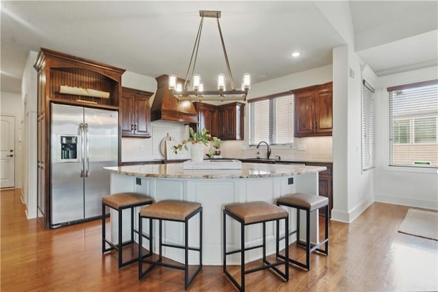 kitchen with stainless steel fridge, backsplash, custom range hood, and a wealth of natural light