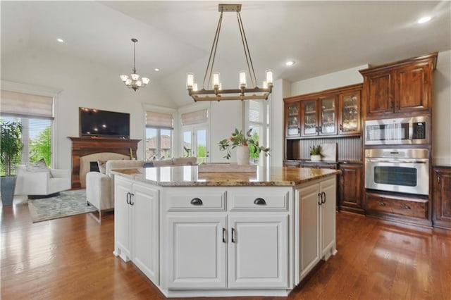 kitchen with dark wood finished floors, a kitchen island, a notable chandelier, and stainless steel appliances