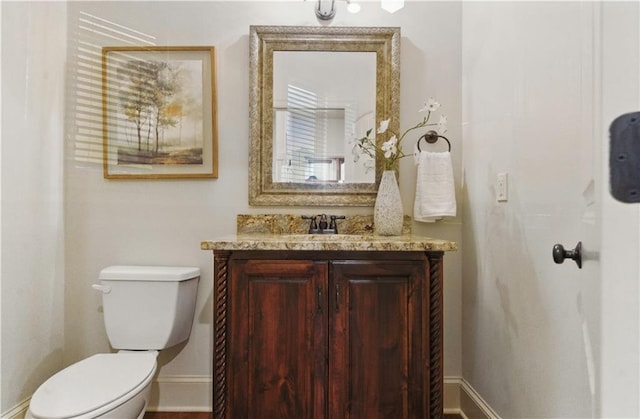 bathroom featuring baseboards, toilet, and vanity