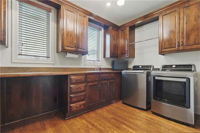 washroom with washing machine and clothes dryer, light wood-type flooring, cabinet space, a sink, and recessed lighting
