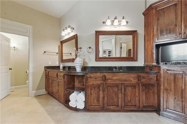 bathroom with tile patterned flooring, double vanity, toilet, baseboards, and a sink