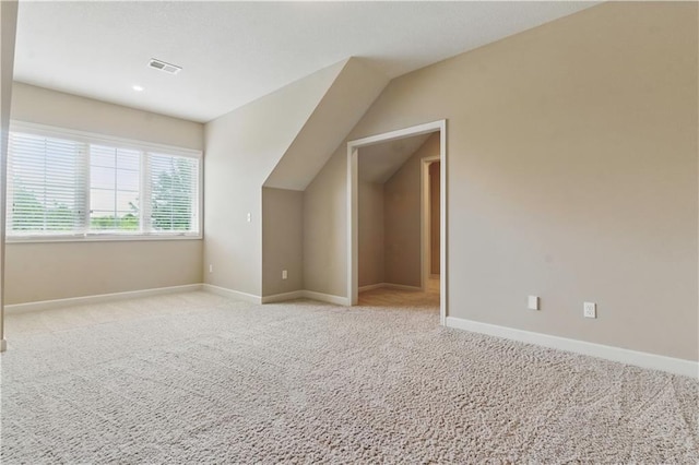 additional living space featuring light colored carpet, baseboards, and visible vents