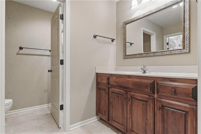 bathroom with toilet, baseboards, tile patterned floors, and vanity