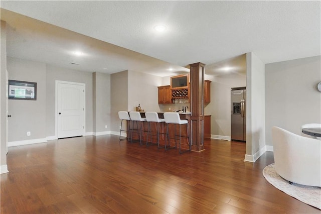 living area featuring baseboards, dark wood-style flooring, and wet bar