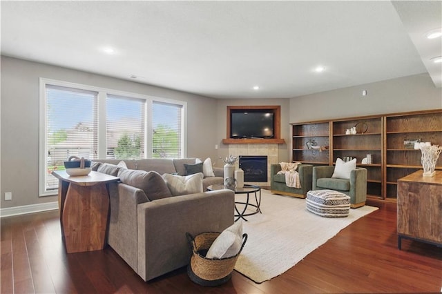 living room featuring dark wood-type flooring, recessed lighting, baseboards, and a fireplace