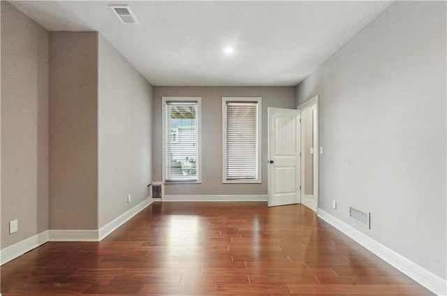 unfurnished room with baseboards, visible vents, and wood finished floors