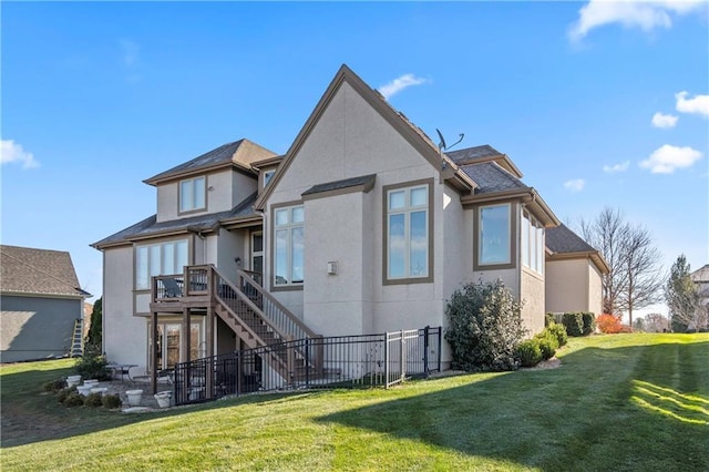 back of property featuring fence, roof with shingles, stucco siding, stairway, and a lawn
