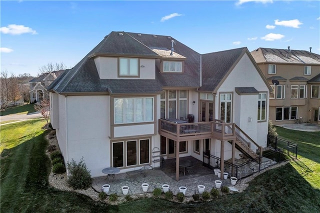 rear view of house featuring stairs, a wooden deck, stucco siding, a lawn, and a patio