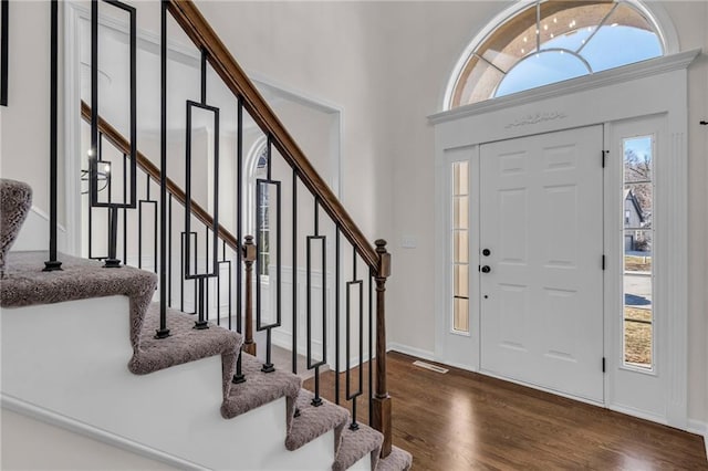 foyer featuring dark wood-style flooring, visible vents, stairway, and baseboards