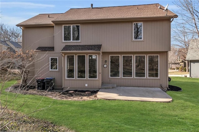 rear view of property featuring a shingled roof, a lawn, and a patio area