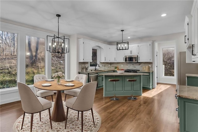 kitchen featuring appliances with stainless steel finishes, a center island, white cabinets, and green cabinetry