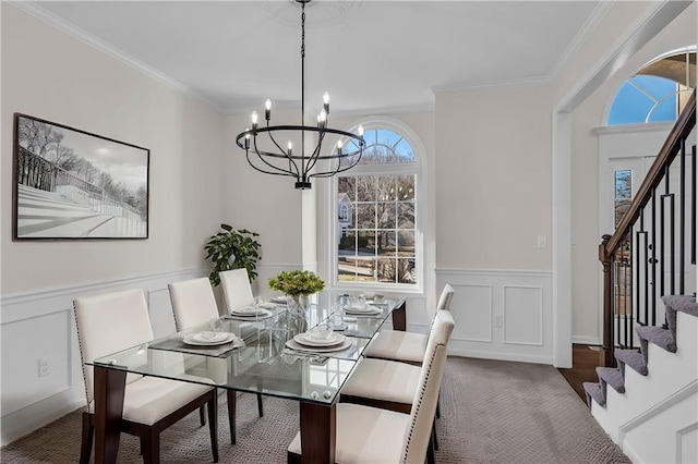 dining room featuring ornamental molding, wainscoting, a notable chandelier, and stairs