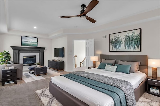 bedroom featuring recessed lighting, a raised ceiling, visible vents, a tiled fireplace, and wood finished floors