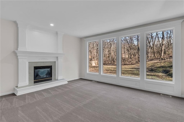 unfurnished living room featuring a healthy amount of sunlight, carpet, a fireplace, and visible vents