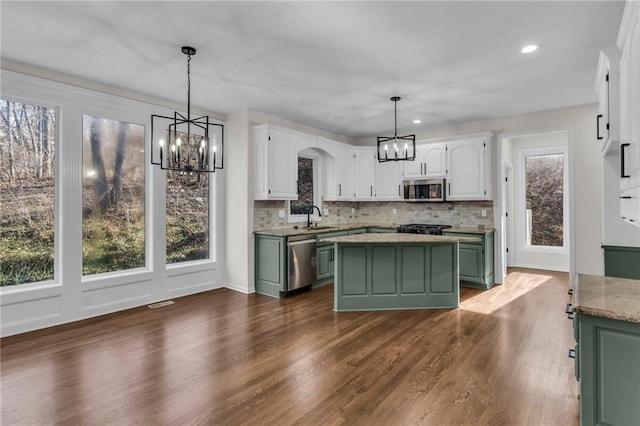 kitchen with green cabinetry, white cabinets, stainless steel appliances, a chandelier, and a sink