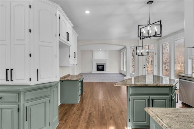 kitchen with a glass covered fireplace, white cabinets, green cabinetry, and stainless steel dishwasher