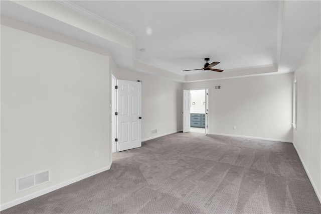 empty room featuring carpet floors, a raised ceiling, visible vents, and baseboards