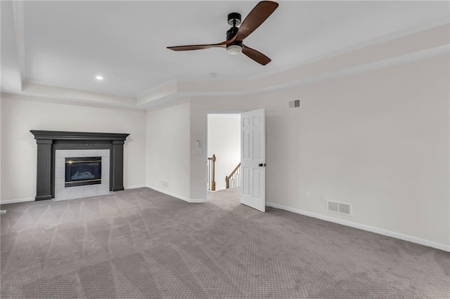 unfurnished living room featuring carpet floors, a raised ceiling, visible vents, and baseboards