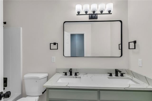 full bathroom with double vanity, a sink, and toilet