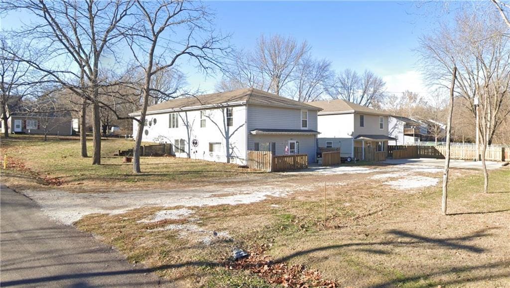 view of side of home featuring driveway, fence, and a residential view