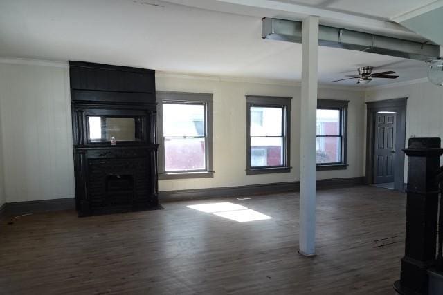 unfurnished living room with dark wood-style flooring, crown molding, and baseboards