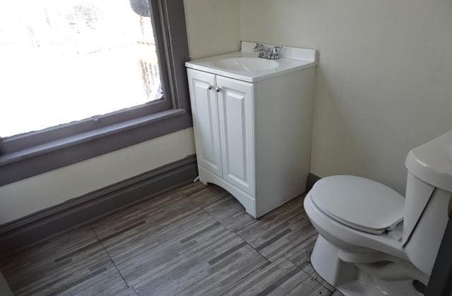 half bath with vanity, toilet, and wood finished floors