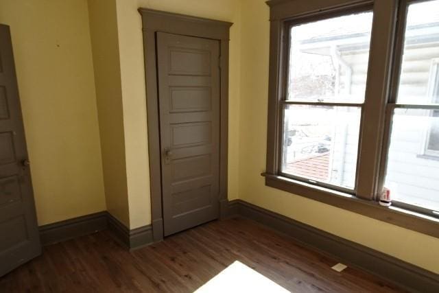 unfurnished room featuring dark wood-type flooring and baseboards