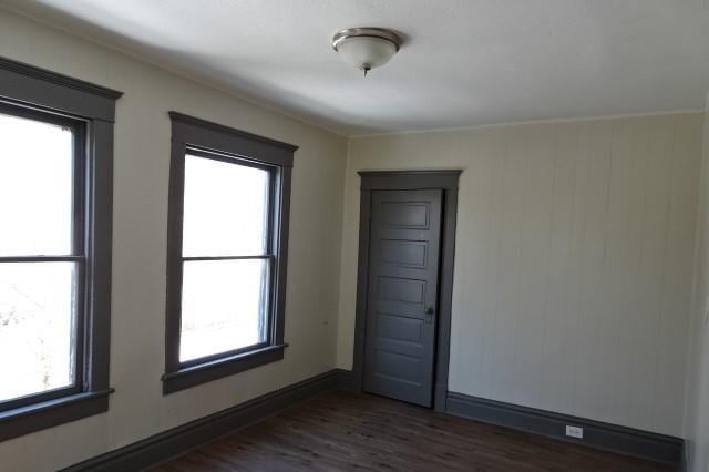 unfurnished room with dark wood-style floors and baseboards