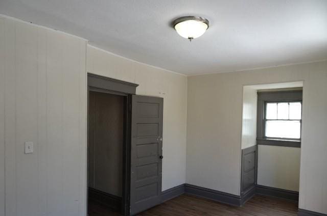 unfurnished room featuring baseboards and dark wood-style flooring