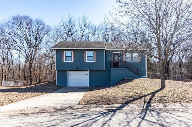 view of front of home with a garage, concrete driveway, and fence