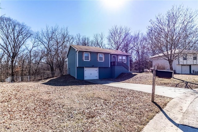 view of front of house with concrete driveway, fence, stairway, and an attached garage