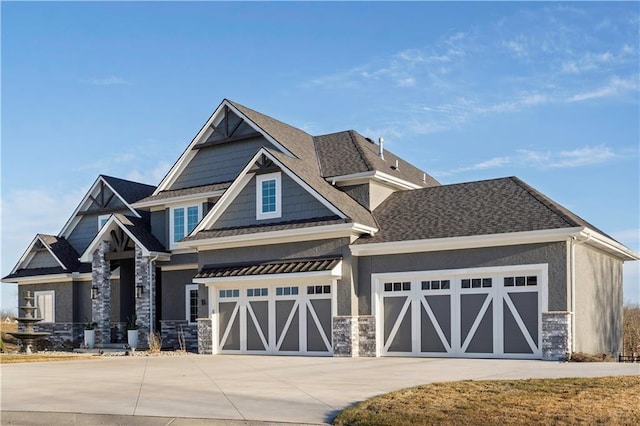 craftsman house with driveway, stone siding, a garage, and stucco siding