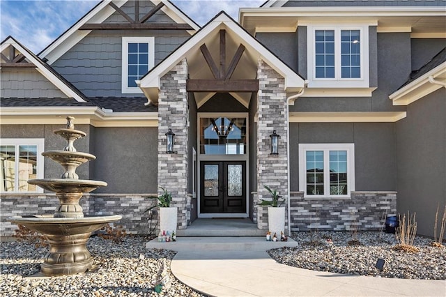 property entrance featuring stone siding, french doors, and stucco siding