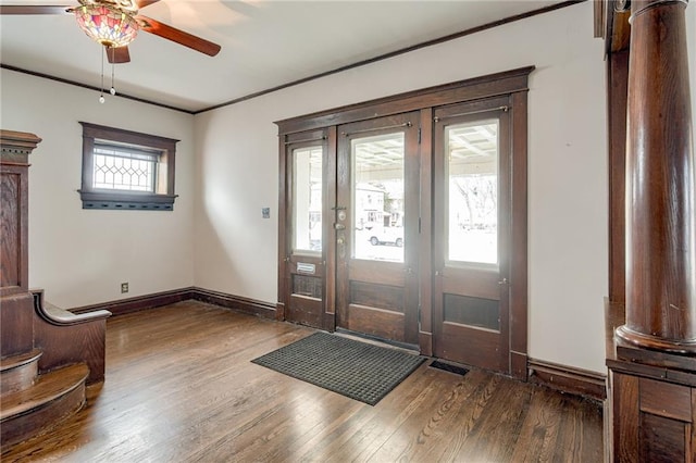 entrance foyer featuring a ceiling fan, crown molding, wood finished floors, and baseboards