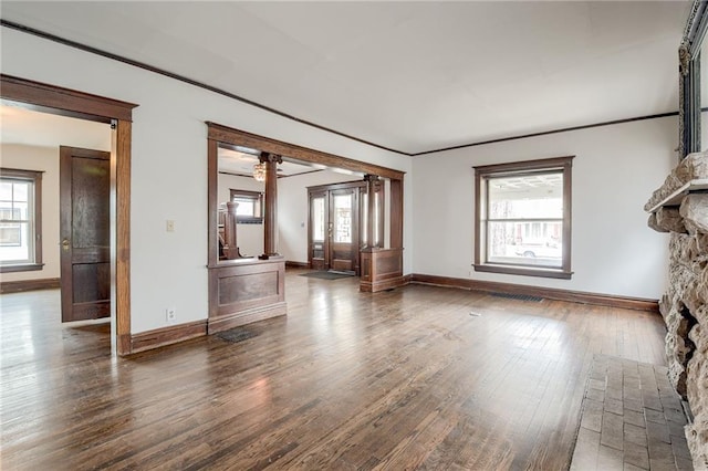 unfurnished living room with baseboards, crown molding, ornate columns, and hardwood / wood-style flooring