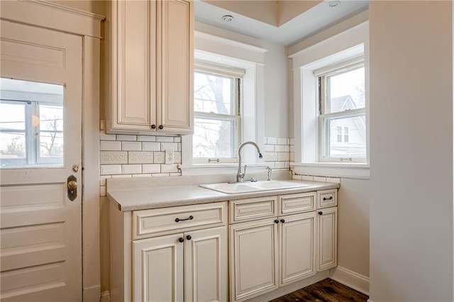 kitchen with decorative backsplash, cream cabinets, a healthy amount of sunlight, and a sink