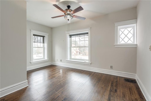 spare room featuring dark wood-style floors, baseboards, and a wealth of natural light